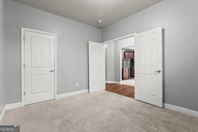 unfurnished bedroom with stainless steel fridge and carpet flooring