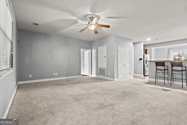 unfurnished living room with light colored carpet and ceiling fan