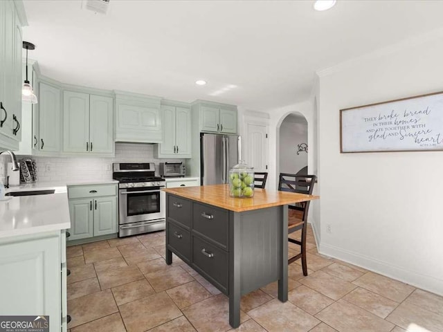 kitchen featuring a kitchen island, butcher block counters, sink, backsplash, and stainless steel appliances