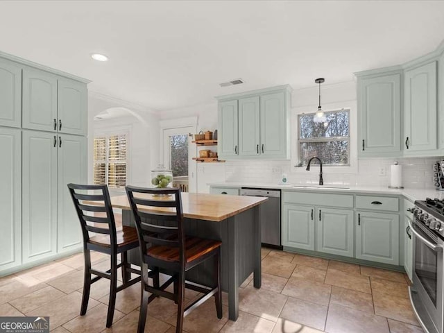 kitchen featuring a wealth of natural light, decorative light fixtures, sink, decorative backsplash, and stainless steel appliances