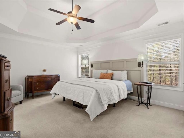 bedroom featuring ceiling fan, light colored carpet, crown molding, and a raised ceiling