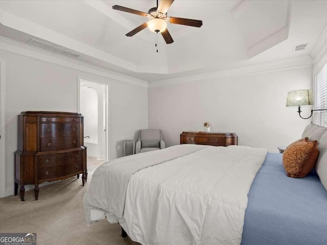 bedroom featuring crown molding, ceiling fan, ensuite bathroom, a tray ceiling, and light colored carpet