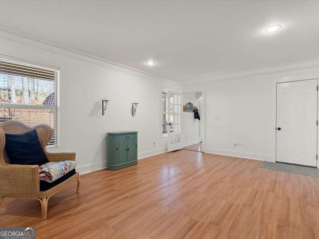 living area with ornamental molding, plenty of natural light, and light hardwood / wood-style flooring