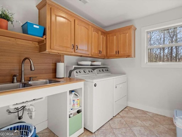 clothes washing area with cabinets, sink, light tile patterned floors, and washing machine and clothes dryer