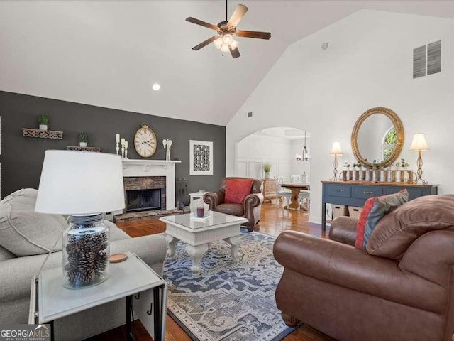 living room with high vaulted ceiling, a stone fireplace, hardwood / wood-style floors, and ceiling fan