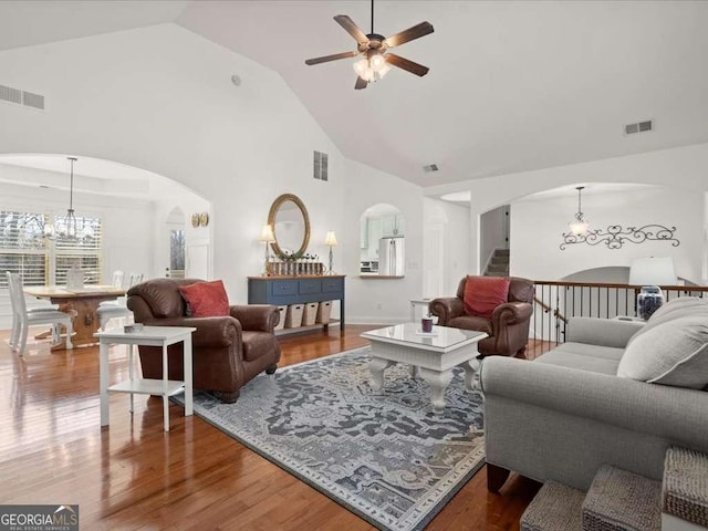 living room featuring hardwood / wood-style flooring, ceiling fan with notable chandelier, and high vaulted ceiling