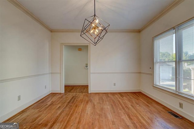 empty room with crown molding, a chandelier, and light hardwood / wood-style flooring