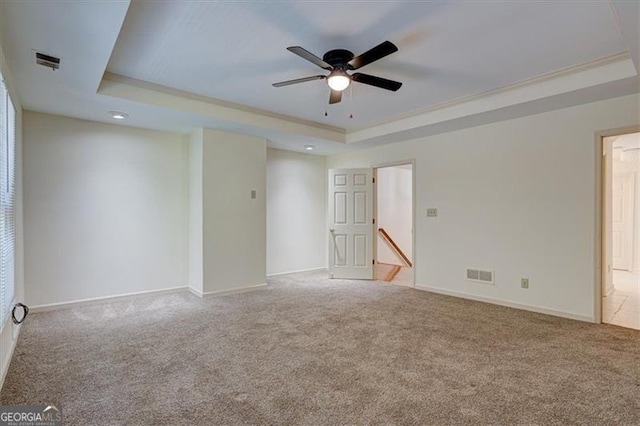 carpeted empty room featuring ceiling fan and a tray ceiling