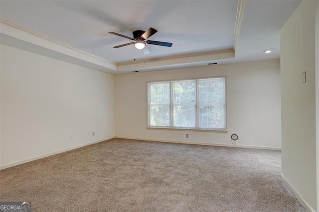 carpeted spare room featuring a raised ceiling, crown molding, and ceiling fan