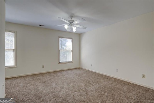 unfurnished room with ceiling fan, light carpet, and a wealth of natural light