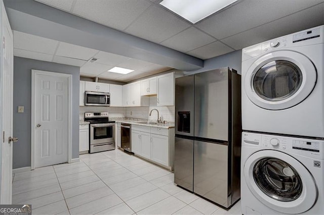 clothes washing area featuring stacked washer and dryer, sink, and light tile patterned floors