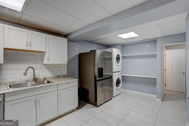 kitchen with white cabinetry, sink, stainless steel appliances, and stacked washer and clothes dryer