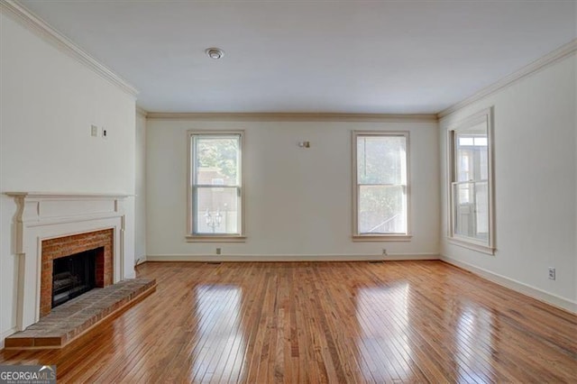 unfurnished living room featuring ornamental molding, light hardwood / wood-style floors, and a brick fireplace