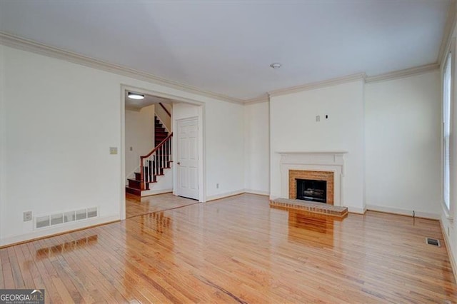 unfurnished living room with hardwood / wood-style floors, crown molding, and a fireplace