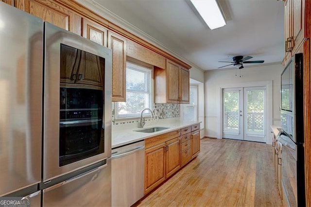 kitchen featuring french doors, sink, crown molding, stainless steel appliances, and light hardwood / wood-style floors