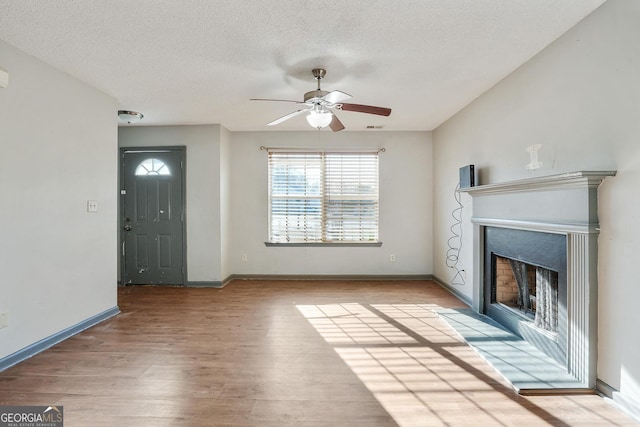 unfurnished living room with ceiling fan, a textured ceiling, and light hardwood / wood-style flooring