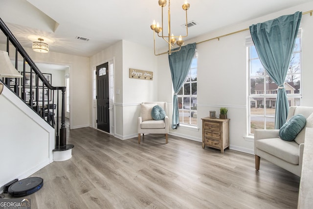 foyer entrance with hardwood / wood-style flooring, a healthy amount of sunlight, and a chandelier