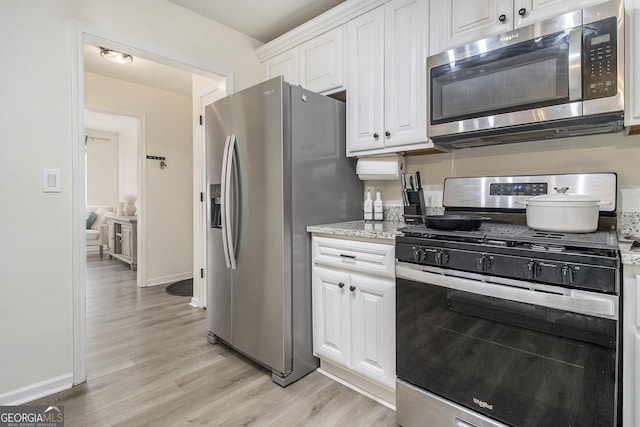 kitchen with white cabinetry, light stone counters, light hardwood / wood-style flooring, and stainless steel appliances