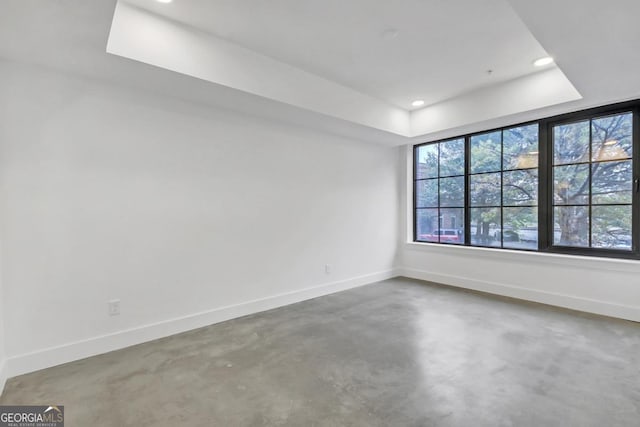 empty room with concrete floors and a tray ceiling