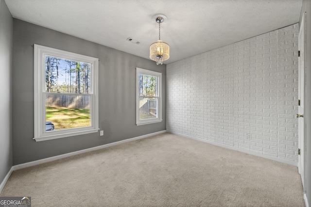 unfurnished room featuring brick wall, a chandelier, light carpet, and a textured ceiling