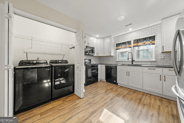 kitchen featuring white cabinetry, sink, independent washer and dryer, and black appliances