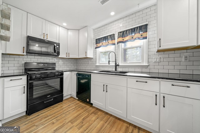 kitchen with sink, black appliances, white cabinets, decorative backsplash, and light wood-type flooring