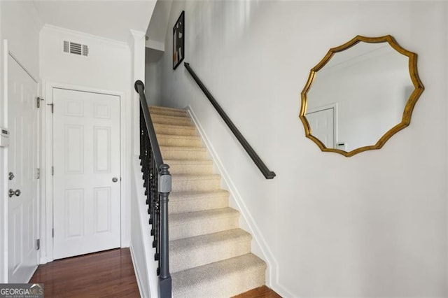 stairway featuring crown molding and wood-type flooring