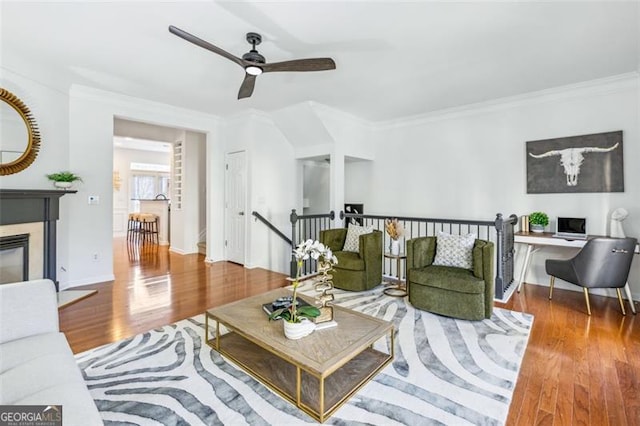 living room featuring hardwood / wood-style flooring, ceiling fan, and crown molding