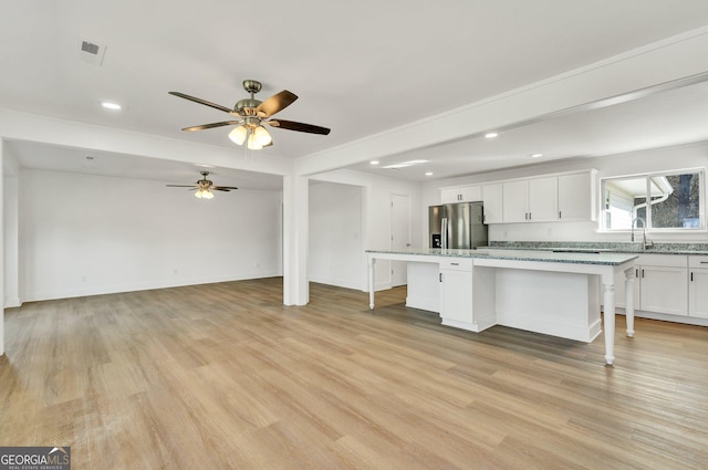 kitchen with white cabinets, a center island, a breakfast bar area, and stainless steel fridge