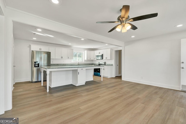 kitchen with a breakfast bar area, white cabinets, a center island, light hardwood / wood-style floors, and stainless steel appliances