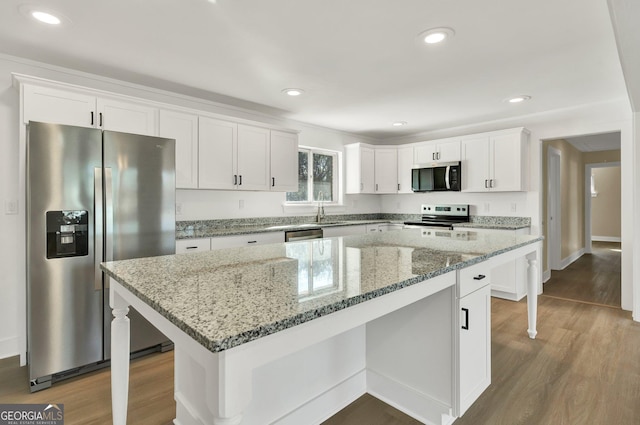 kitchen featuring white cabinetry, appliances with stainless steel finishes, a center island, and light stone countertops