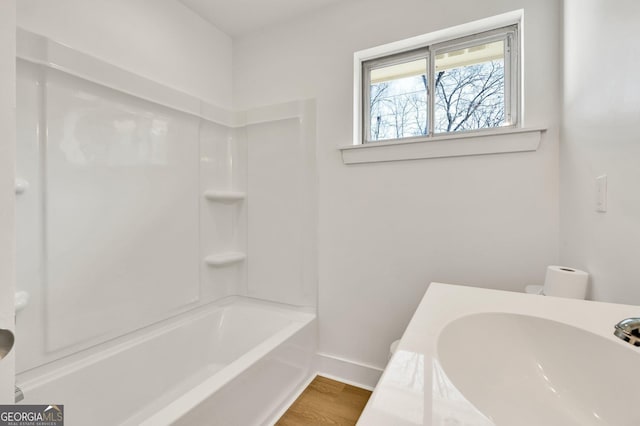 full bathroom featuring sink, hardwood / wood-style floors, toilet, and washtub / shower combination