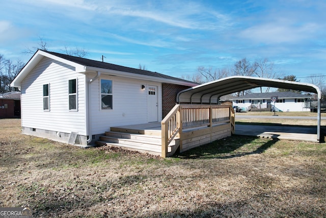 view of front of property featuring a carport, a deck, and a front lawn