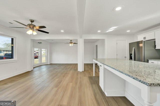 kitchen featuring white cabinetry, light wood-type flooring, stainless steel fridge, ceiling fan, and light stone countertops