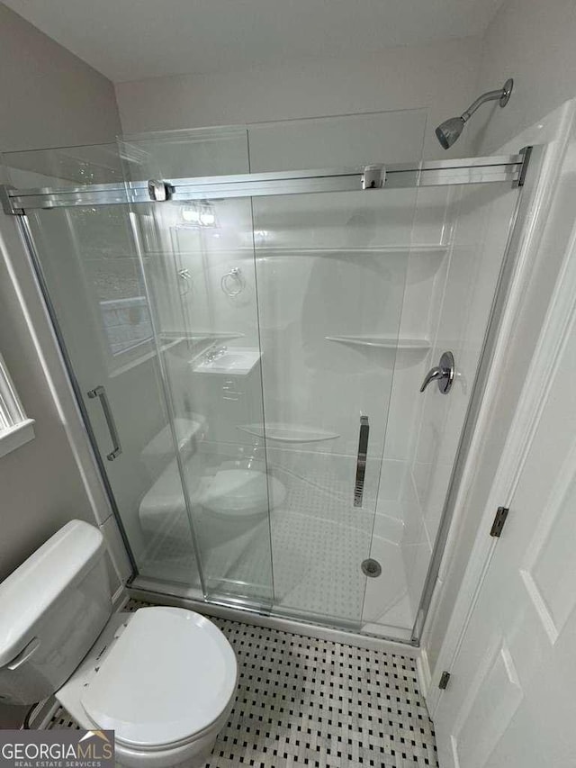 bathroom featuring tile patterned flooring, toilet, and walk in shower