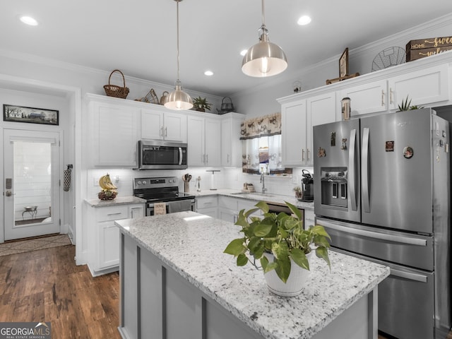 kitchen featuring crown molding, hanging light fixtures, a kitchen island, stainless steel appliances, and white cabinets