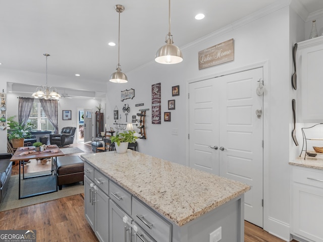 kitchen featuring pendant lighting, wood-type flooring, ornamental molding, and a kitchen island