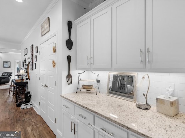 interior space featuring light stone counters, ornamental molding, dark wood-type flooring, and white cabinets