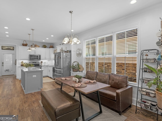 dining area with an inviting chandelier, crown molding, and light hardwood / wood-style floors