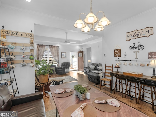 dining room with crown molding, wood-type flooring, and ceiling fan with notable chandelier