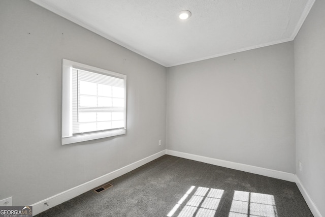 spare room with ornamental molding and dark carpet