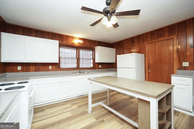 kitchen featuring white appliances, light hardwood / wood-style flooring, white cabinets, and wood walls