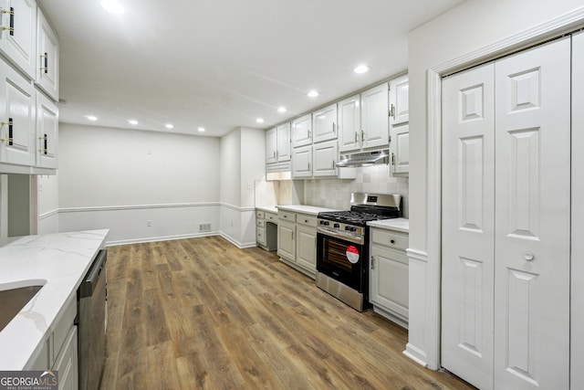 kitchen featuring hardwood / wood-style floors, stainless steel appliances, light stone countertops, white cabinets, and decorative backsplash