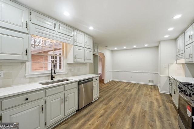 kitchen with sink, hardwood / wood-style floors, stainless steel appliances, tasteful backsplash, and white cabinets