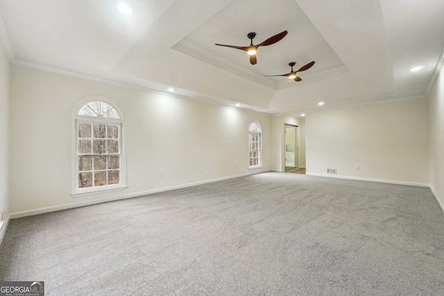 carpeted spare room with a raised ceiling, crown molding, and ceiling fan