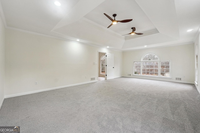 carpeted spare room with crown molding, ceiling fan, and a tray ceiling