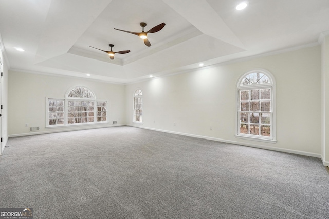 carpeted empty room with a tray ceiling, ornamental molding, and ceiling fan