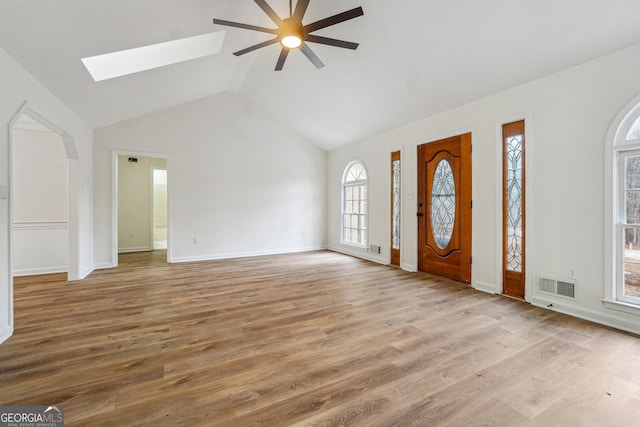 foyer entrance featuring ceiling fan, lofted ceiling with skylight, and light wood-type flooring