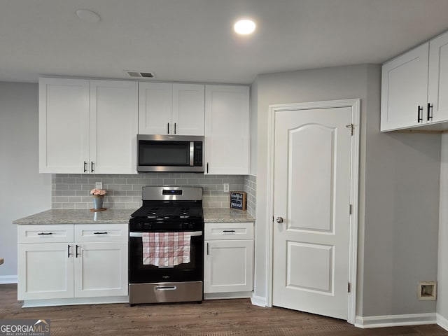 kitchen featuring white cabinets, dark hardwood / wood-style flooring, decorative backsplash, light stone counters, and stainless steel appliances