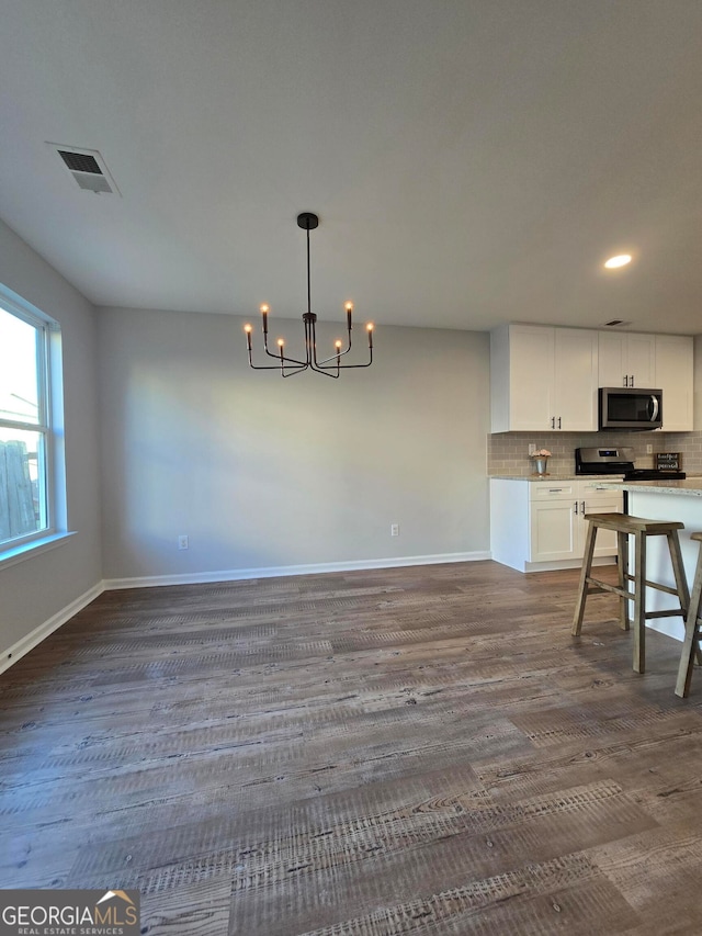 kitchen with white cabinetry, tasteful backsplash, an inviting chandelier, hanging light fixtures, and dark hardwood / wood-style floors